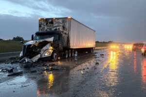 Semi-trailer truck accident on wet freeway during evening hours leads to significant road obstruction